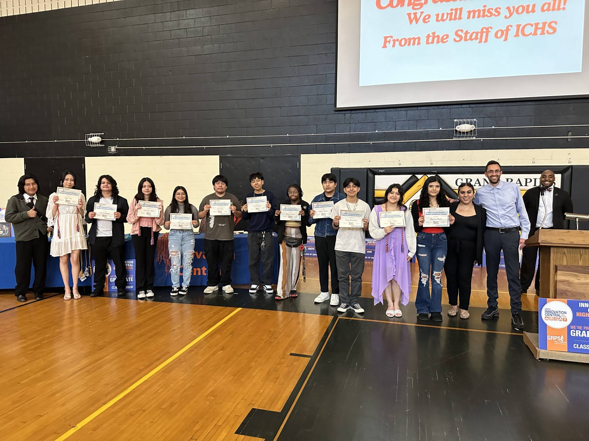 group of Upward Bound students standing smiling at the camera in a straight line with awards